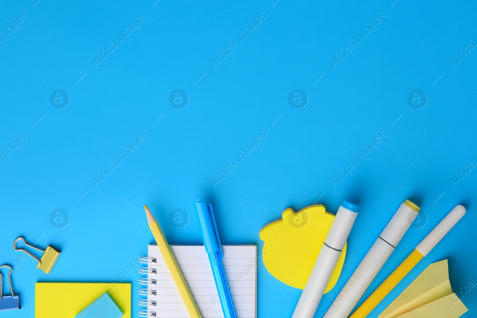 Photo of Paper plane and different school stationery on light blue background, flat lay with space for text. Back to school