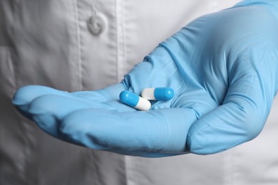 Photo of Doctor in medical glove holding pills, closeup view