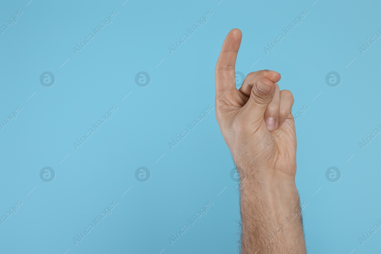 Photo of Man snapping fingers on light blue background, closeup of hand. Space for text