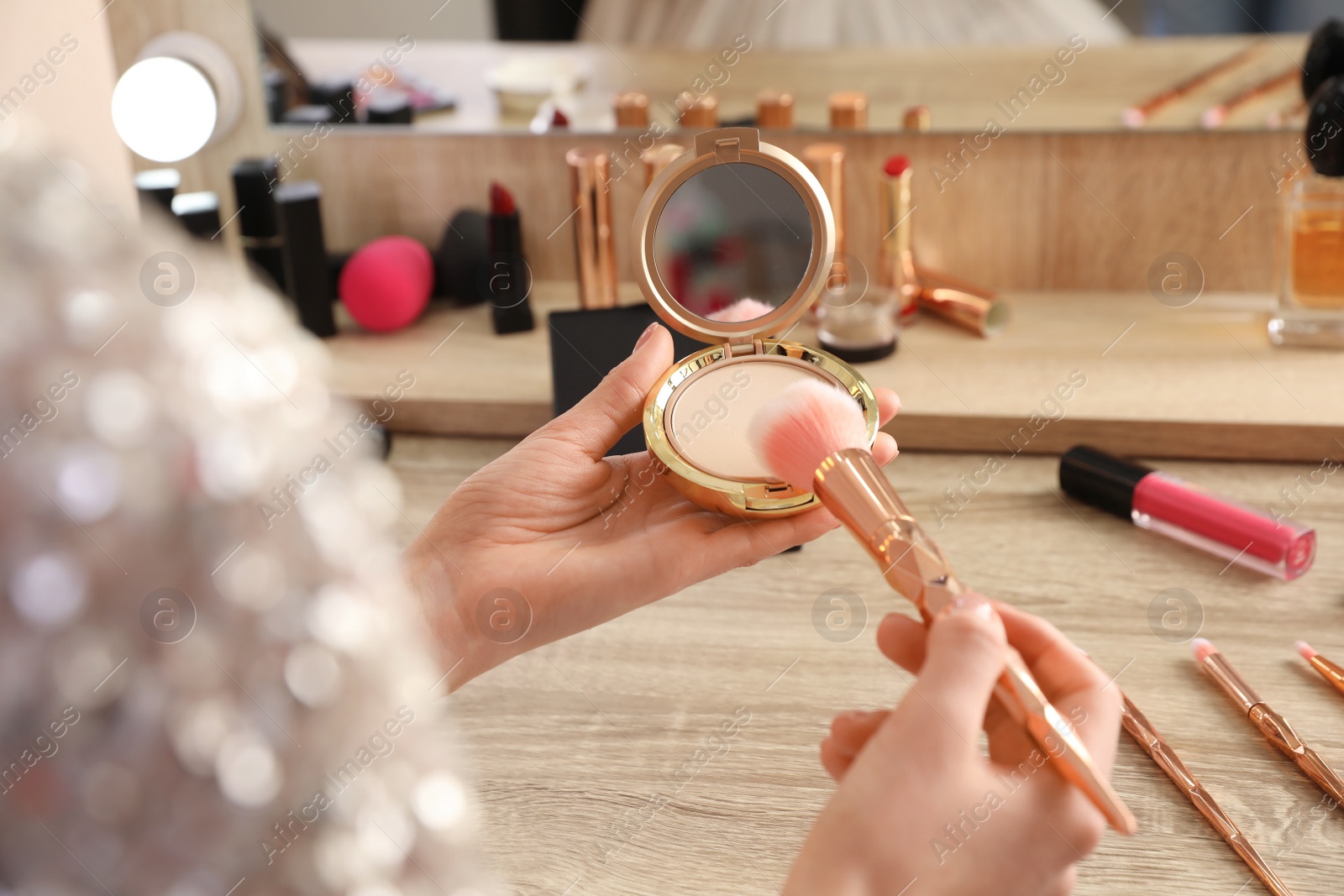 Photo of Woman applying makeup at dressing table, closeup