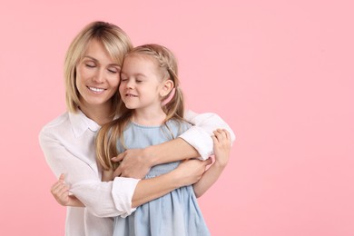 Photo of Mother hugging her happy daughter on pink background. Space for text