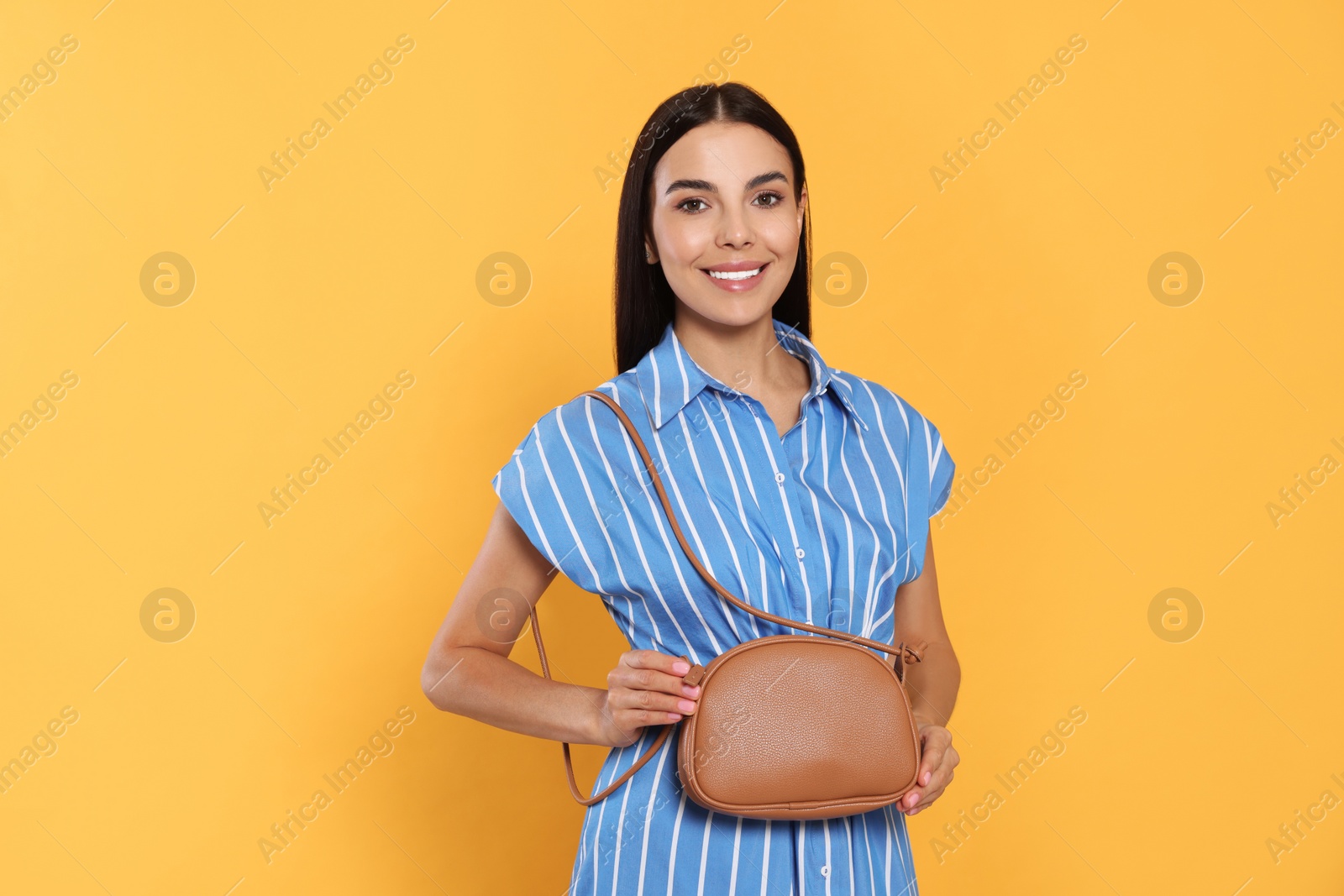 Photo of Beautiful young woman with stylish bag on orange background