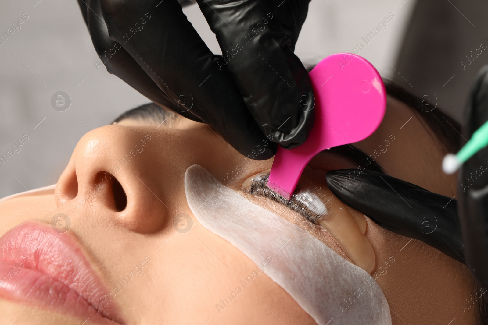 Photo of Young woman undergoing eyelash lamination, closeup. Professional service