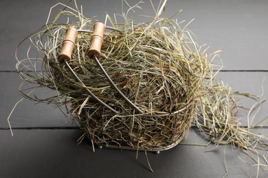 Photo of Dried hay in metal basket on grey wooden table