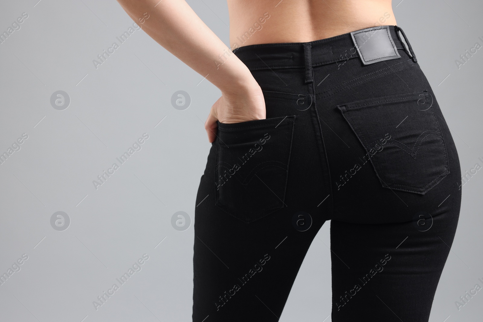 Photo of Woman wearing stylish black jeans on light gray background, closeup. Space for text