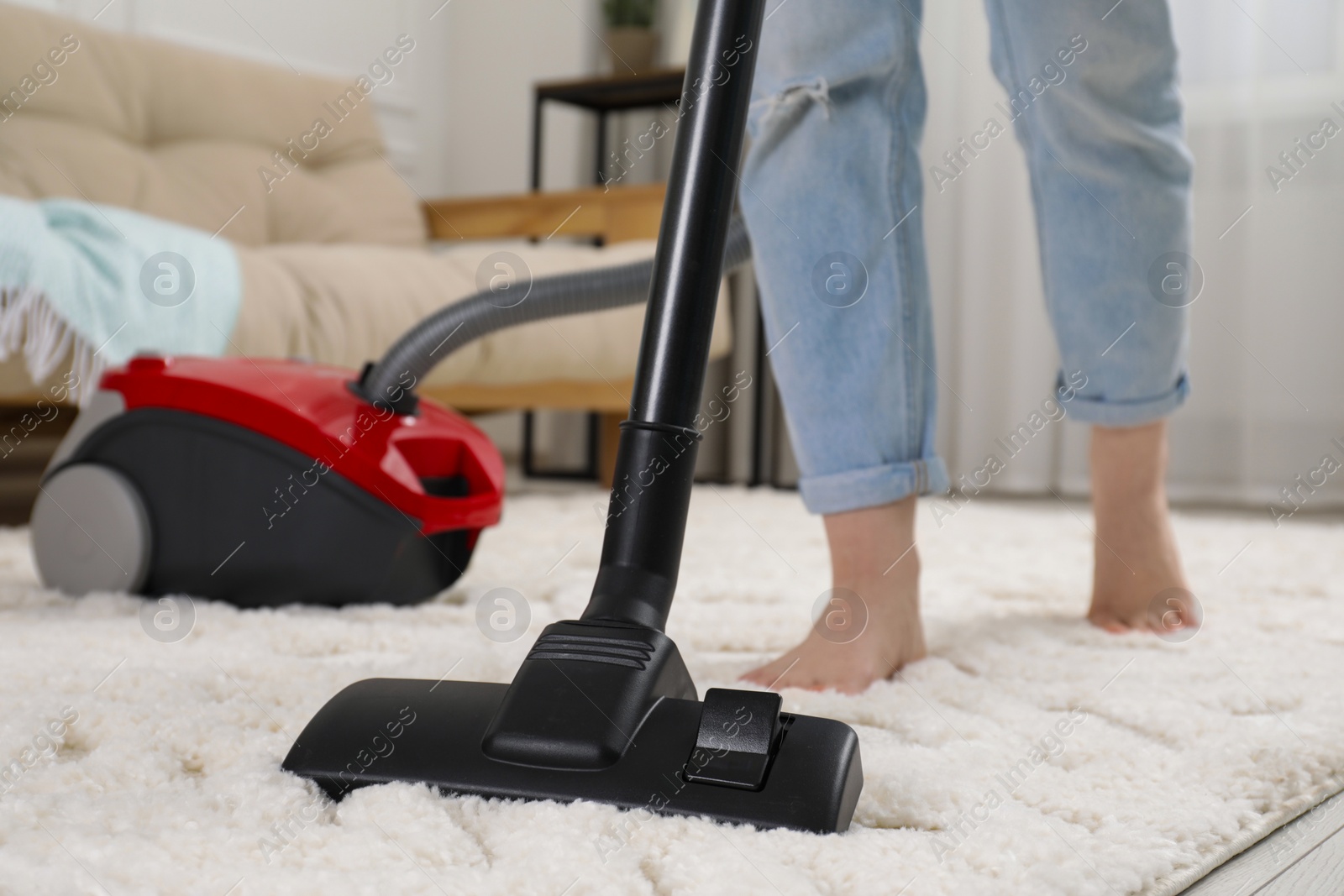 Photo of Woman cleaning carpet with vacuum cleaner at home, closeup