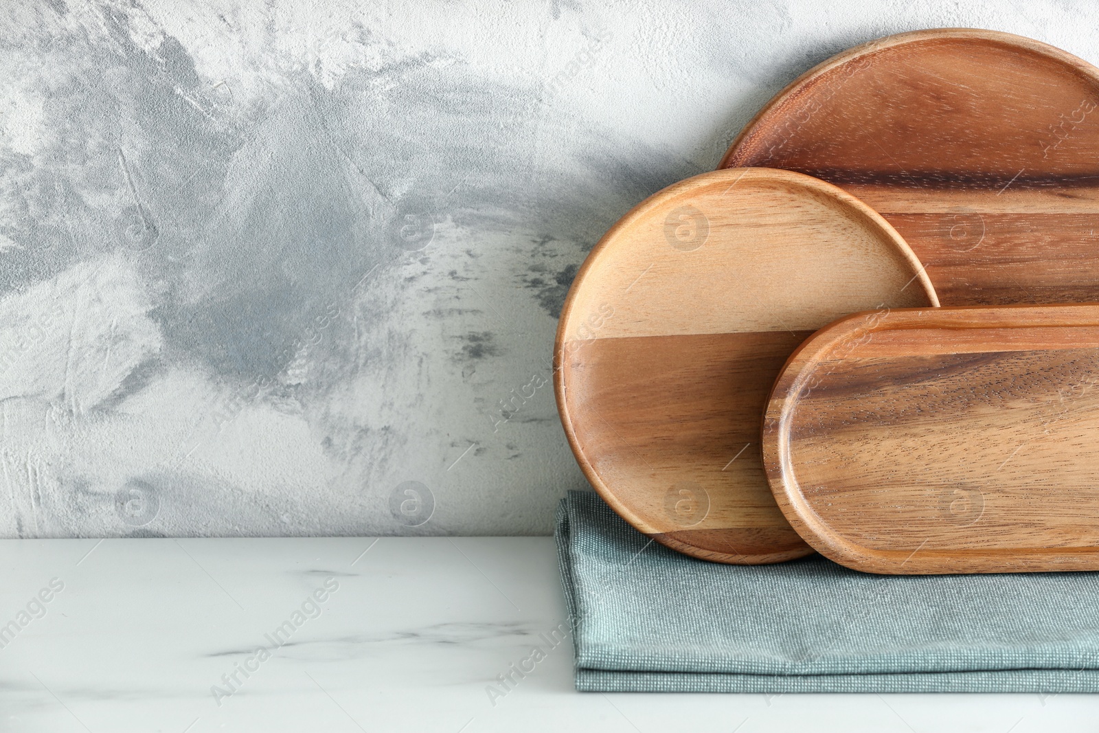 Photo of Set of wooden dishware on white marble table against textured wall. Space for text