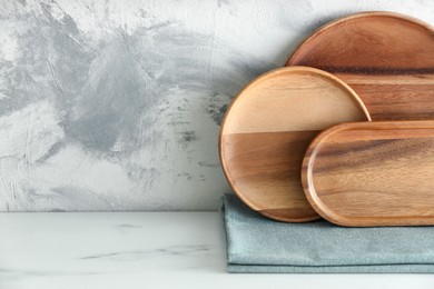 Photo of Set of wooden dishware on white marble table against textured wall. Space for text