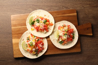 Photo of Delicious tacos with vegetables and lime on wooden table, top view