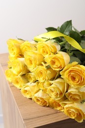 Beautiful bouquet of yellow roses on wooden table