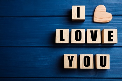 Cubes with words I Love You and heart on blue wooden background, flat lay. Space for text