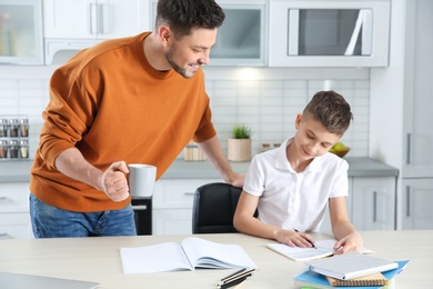 Photo of Dad helping his son with homework in kitchen