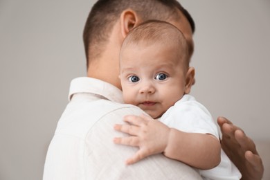 Photo of Father holding his cute baby on grey background