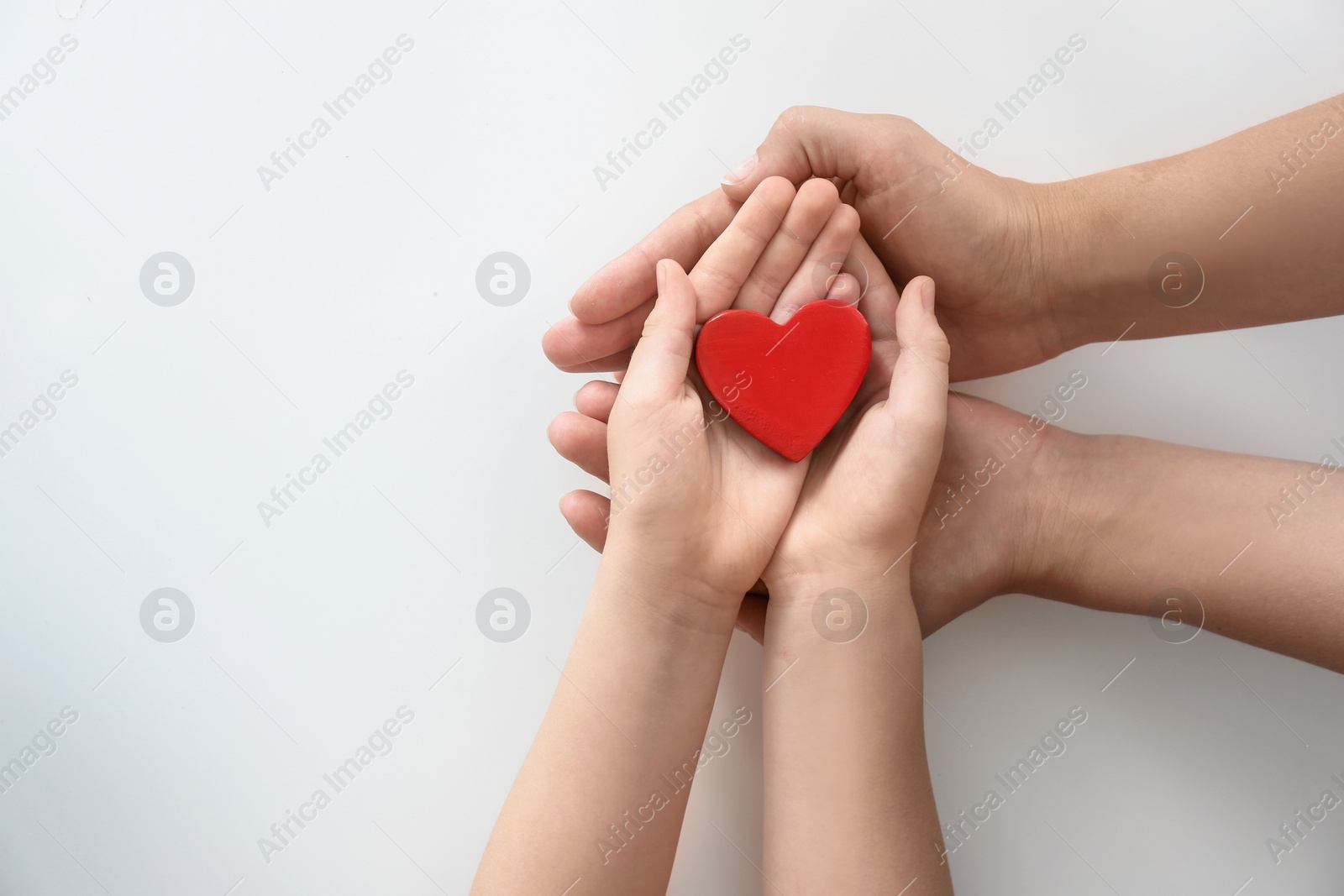 Photo of Young woman and child holding red heart on light background, top view