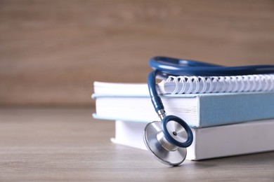 Photo of Closeup view of student textbooks and stethoscope on wooden table, space for text. Medical education