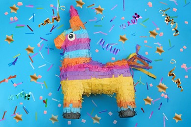 Image of Bright funny pinata and party decor on blue background, flat lay