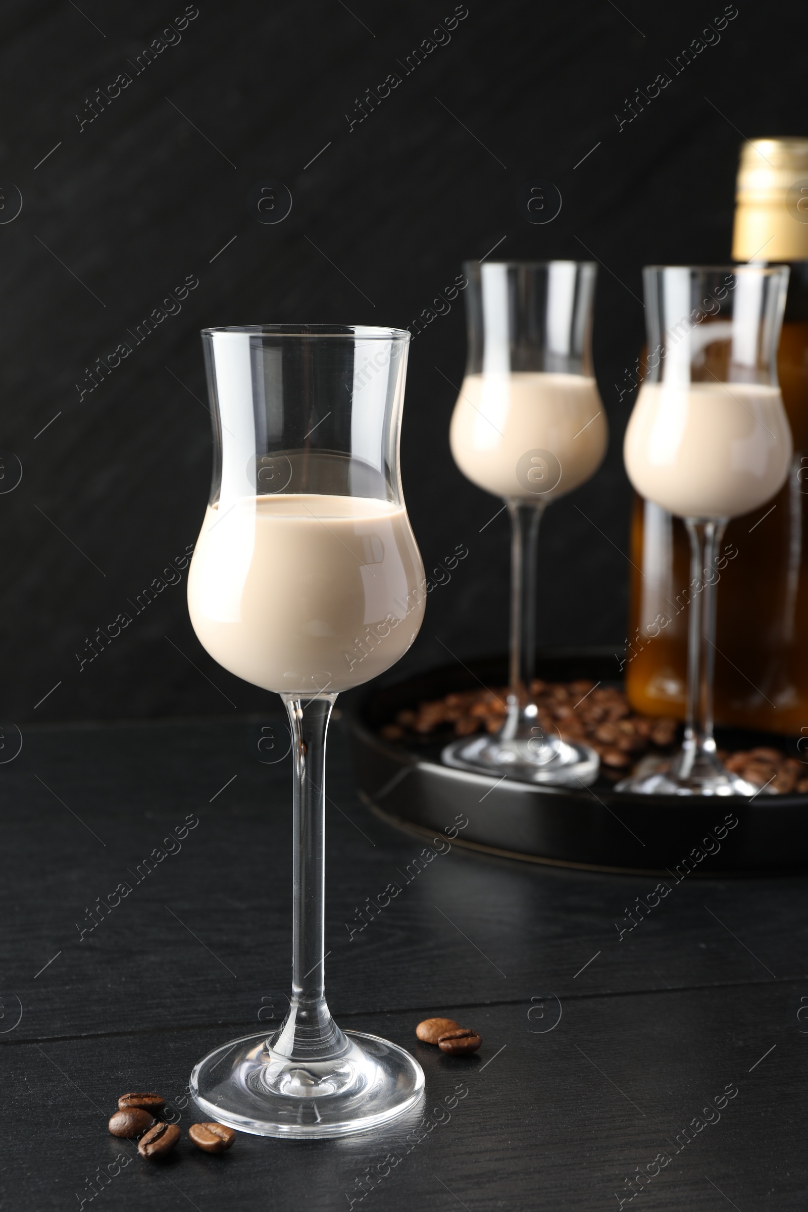 Photo of Coffee cream liqueur in glasses and beans on black wooden table