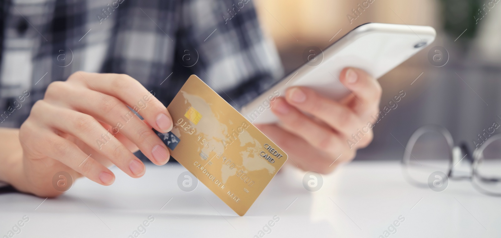 Image of Woman with credit card using smartphone for online payment at table, closeup. Banner design