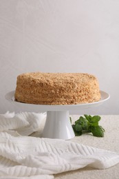 Photo of Delicious Napoleon cake and mint on table against light background, space for text