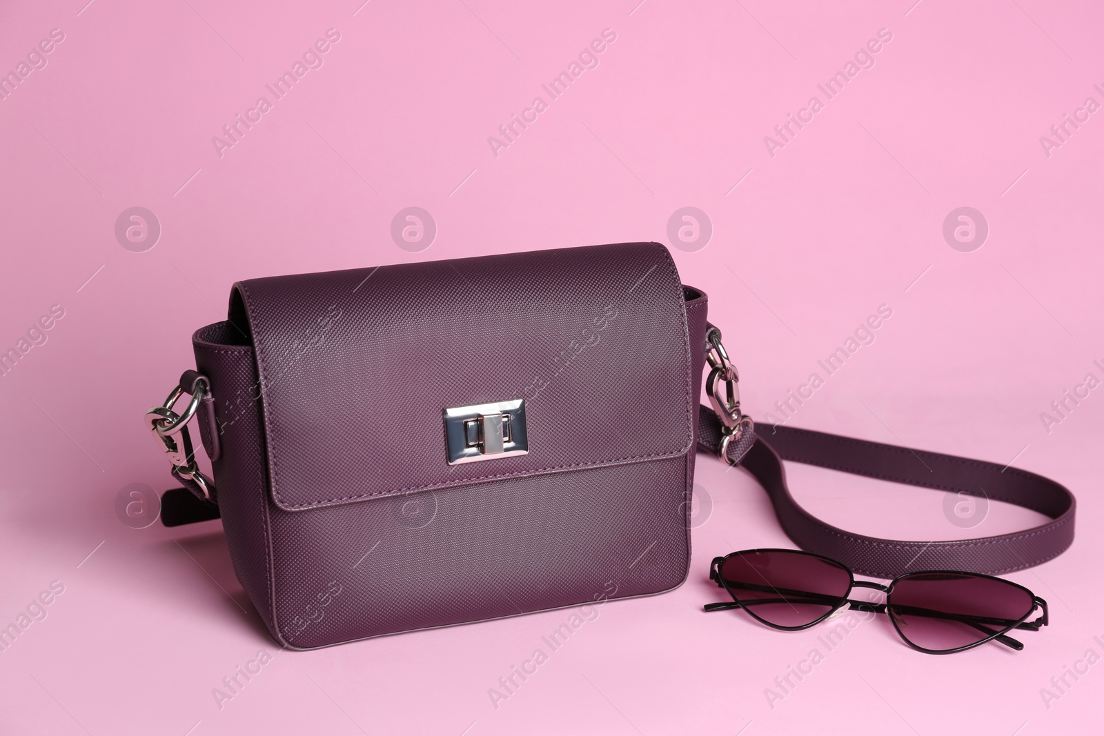 Photo of Stylish woman's bag and sunglasses on light pink background