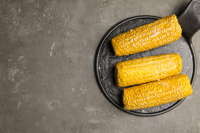 Photo of Delicious boiled corn with butter and salt on grey table, top view. Space for text