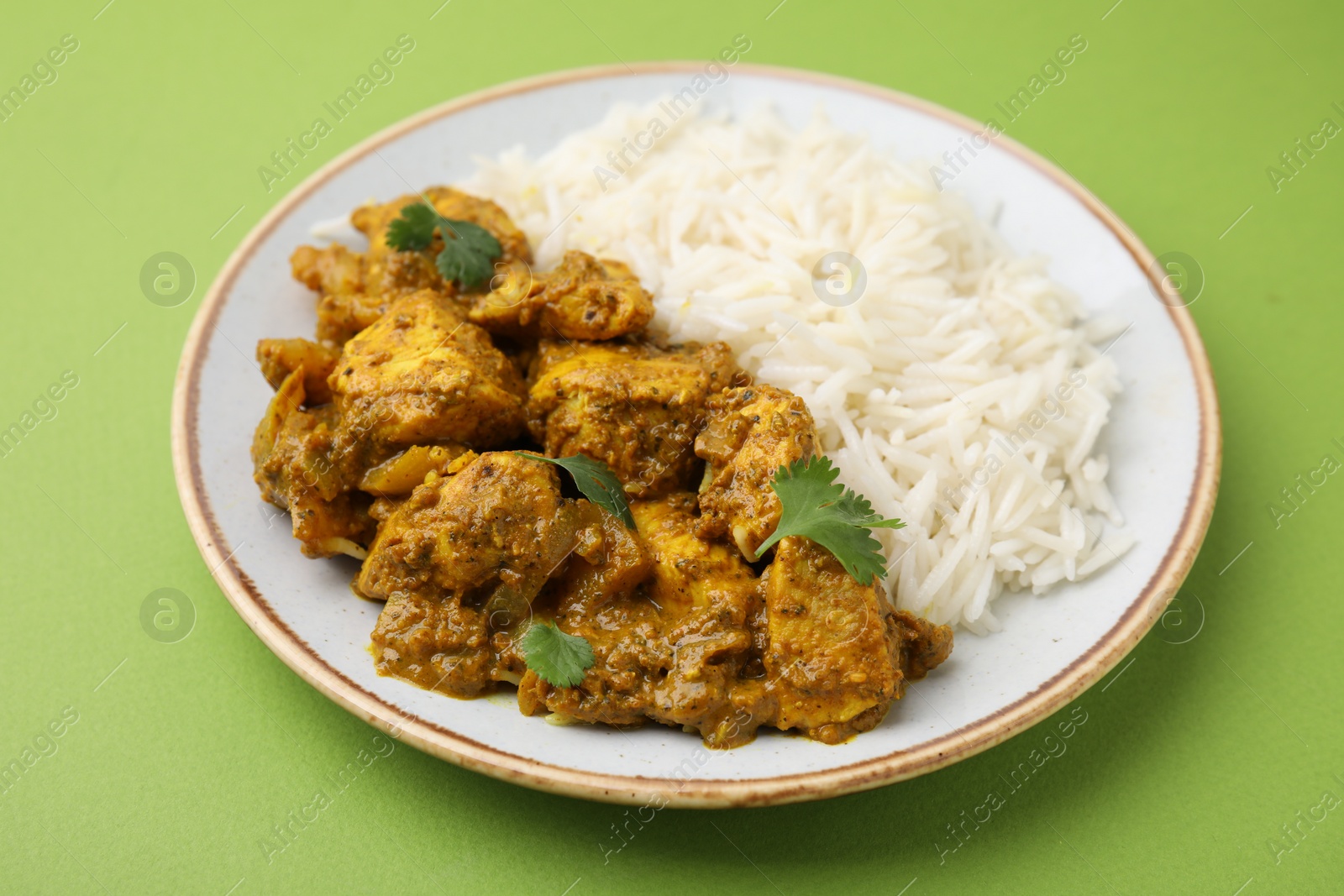 Photo of Delicious chicken curry with rice on green background, closeup