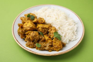 Photo of Delicious chicken curry with rice on green background, closeup