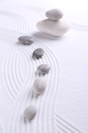 Photo of Zen garden stones on white sand with pattern