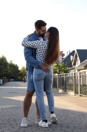 Happy couple dancing and kissing outdoors on sunny day