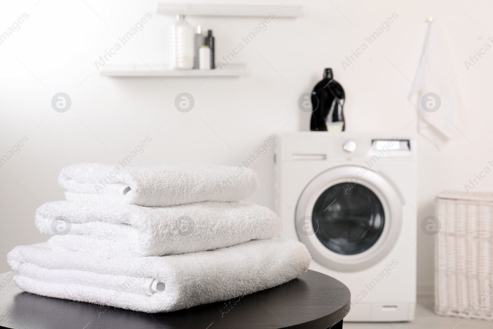 Photo of Stack of clean soft towels on table in laundry room. Space for text