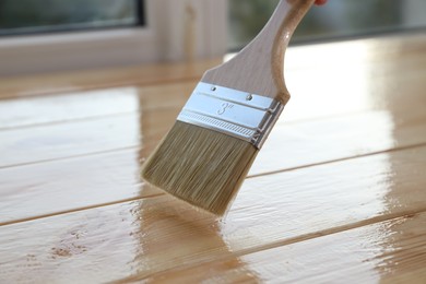 Varnishing wooden surface with brush, closeup view