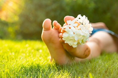 Photo of Teenage girl with beautiful hortensia flowers lying on green grass outdoors, closeup