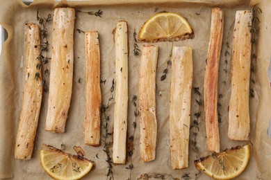 Photo of Baking tray with cooked salsify roots, lemon and thyme as background, closeup