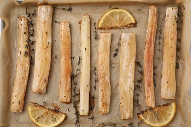 Baking tray with cooked salsify roots, lemon and thyme as background, closeup