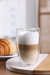 Photo of Aromatic latte macchiato in glass and croissant on wooden table against blurred background