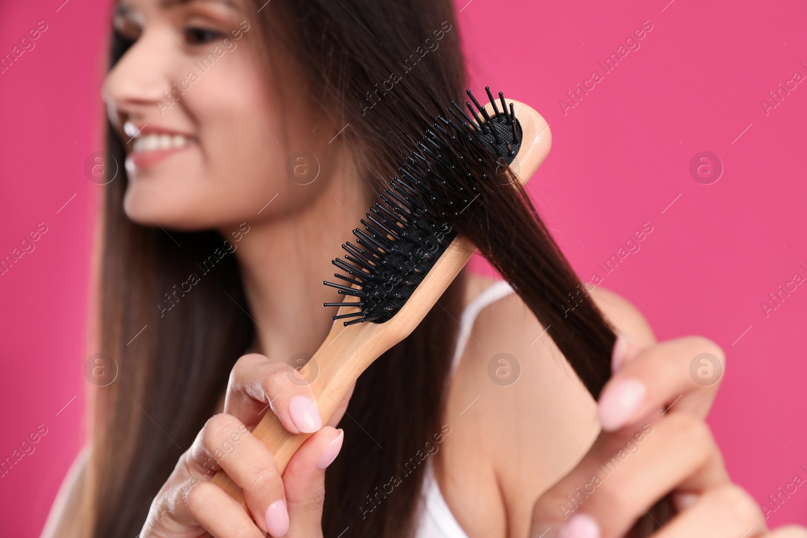 Photo of Beautiful smiling young woman with hair brush on color background