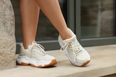 Photo of Woman wearing pair of stylish sneakers outdoors, closeup