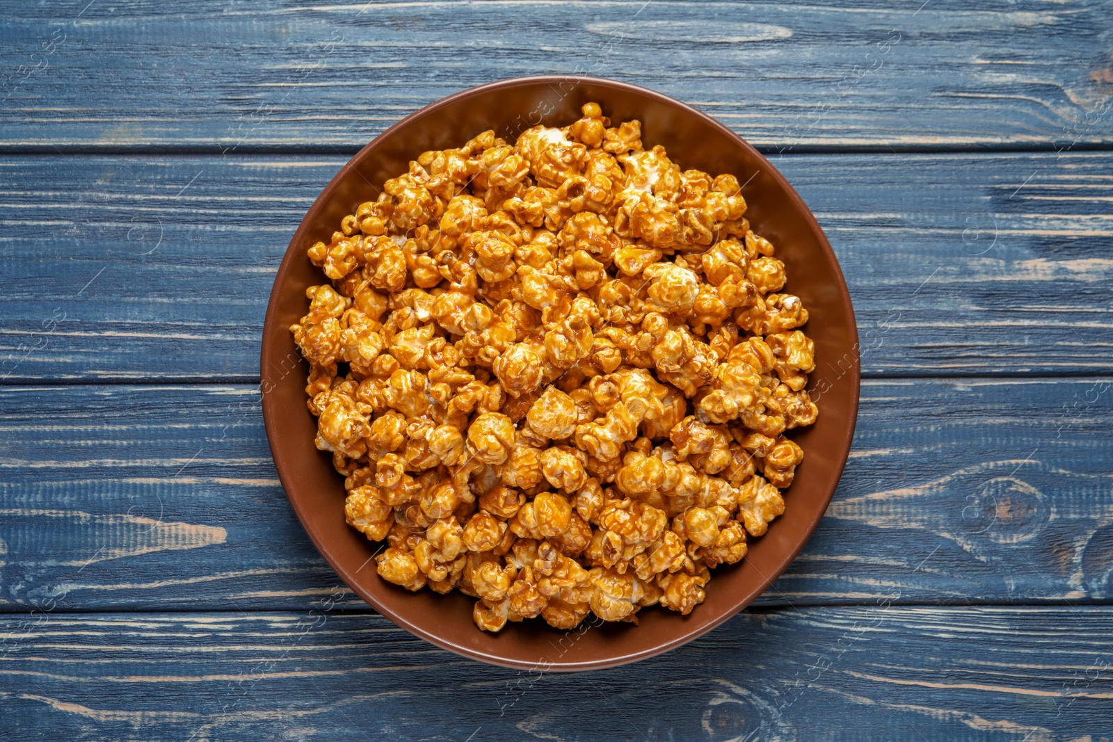 Photo of Delicious popcorn with caramel on wooden background, top view