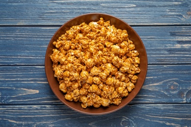 Photo of Delicious popcorn with caramel on wooden background, top view