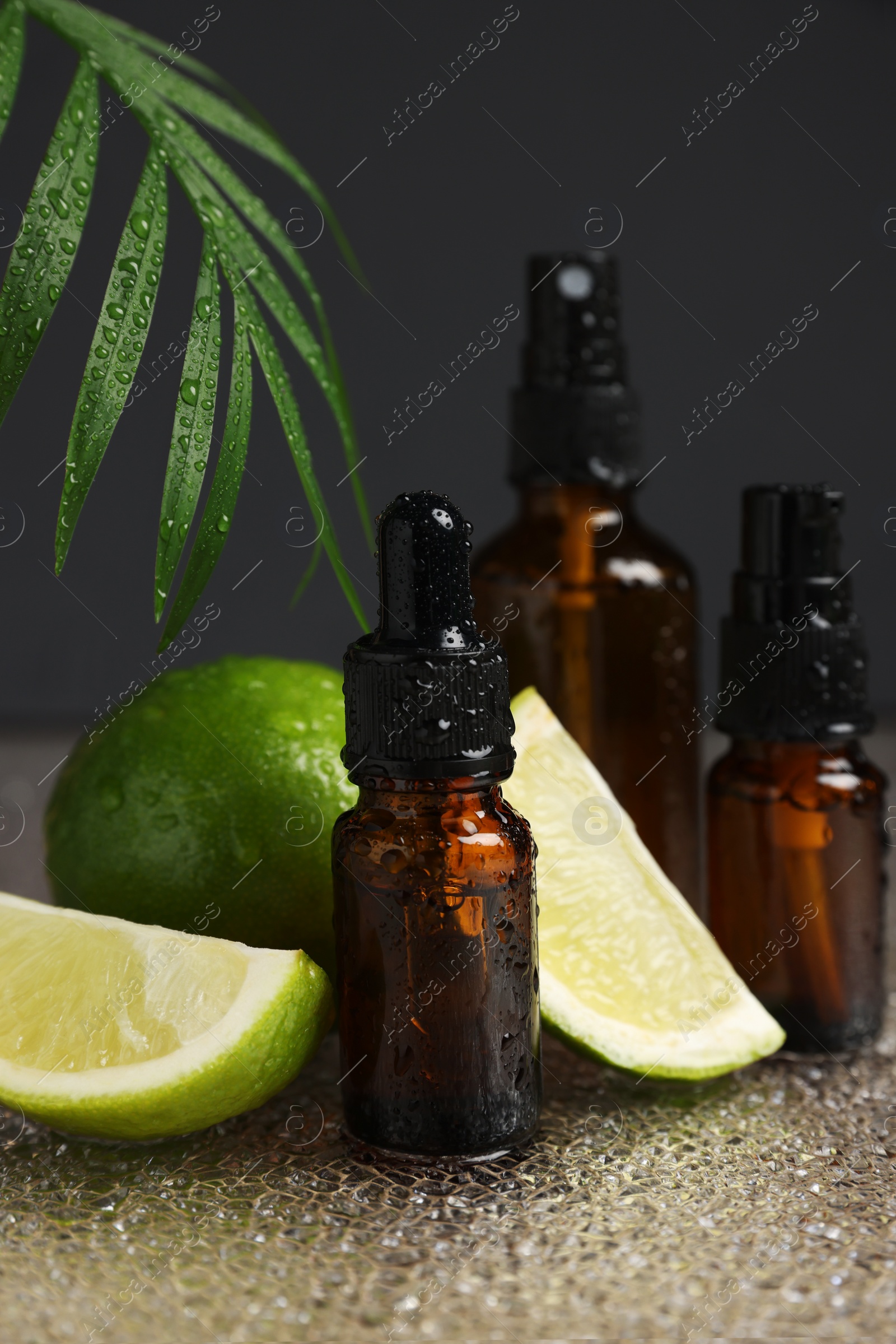 Photo of Bottles of organic cosmetic products and sliced lime on wet surface