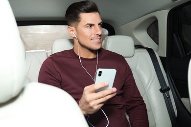 Man with mobile phone listening to audiobook in car