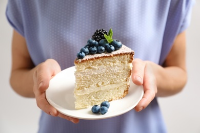 Woman holding piece of delicious homemade cake with fresh berries on plate, closeup