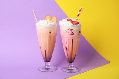 Photo of Glasses of tasty milk shakes on color background