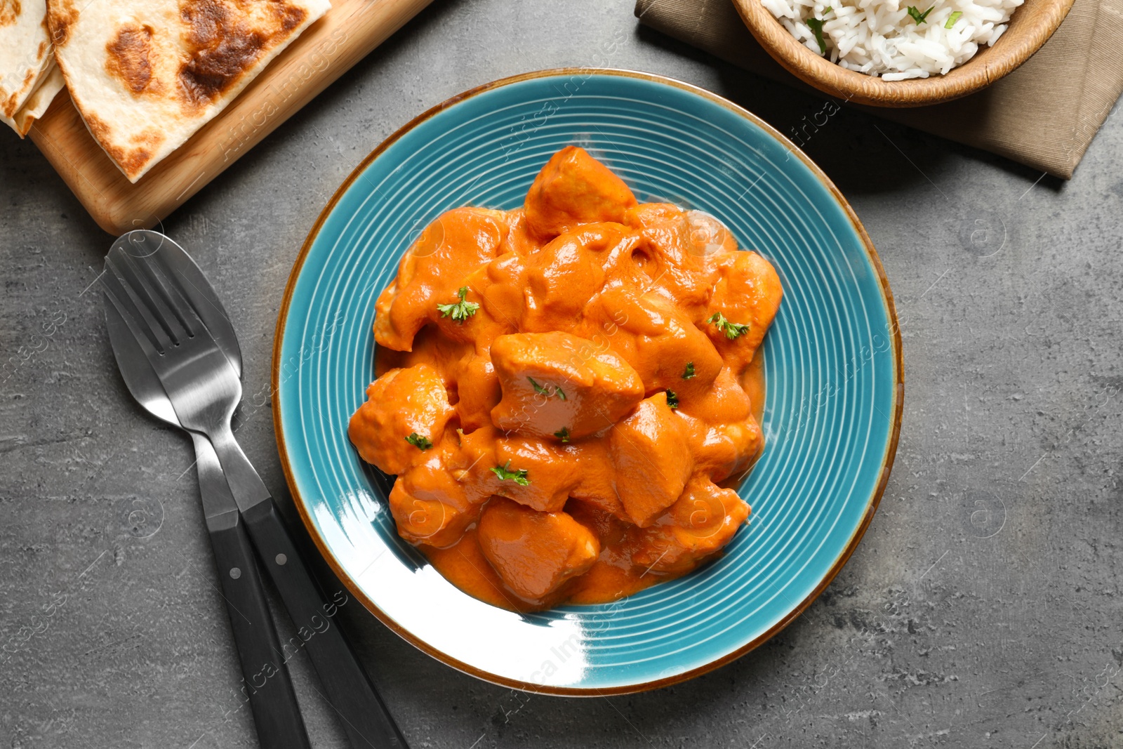 Photo of Butter chicken served on grey table, flat lay. Traditional indian Murgh Makhani