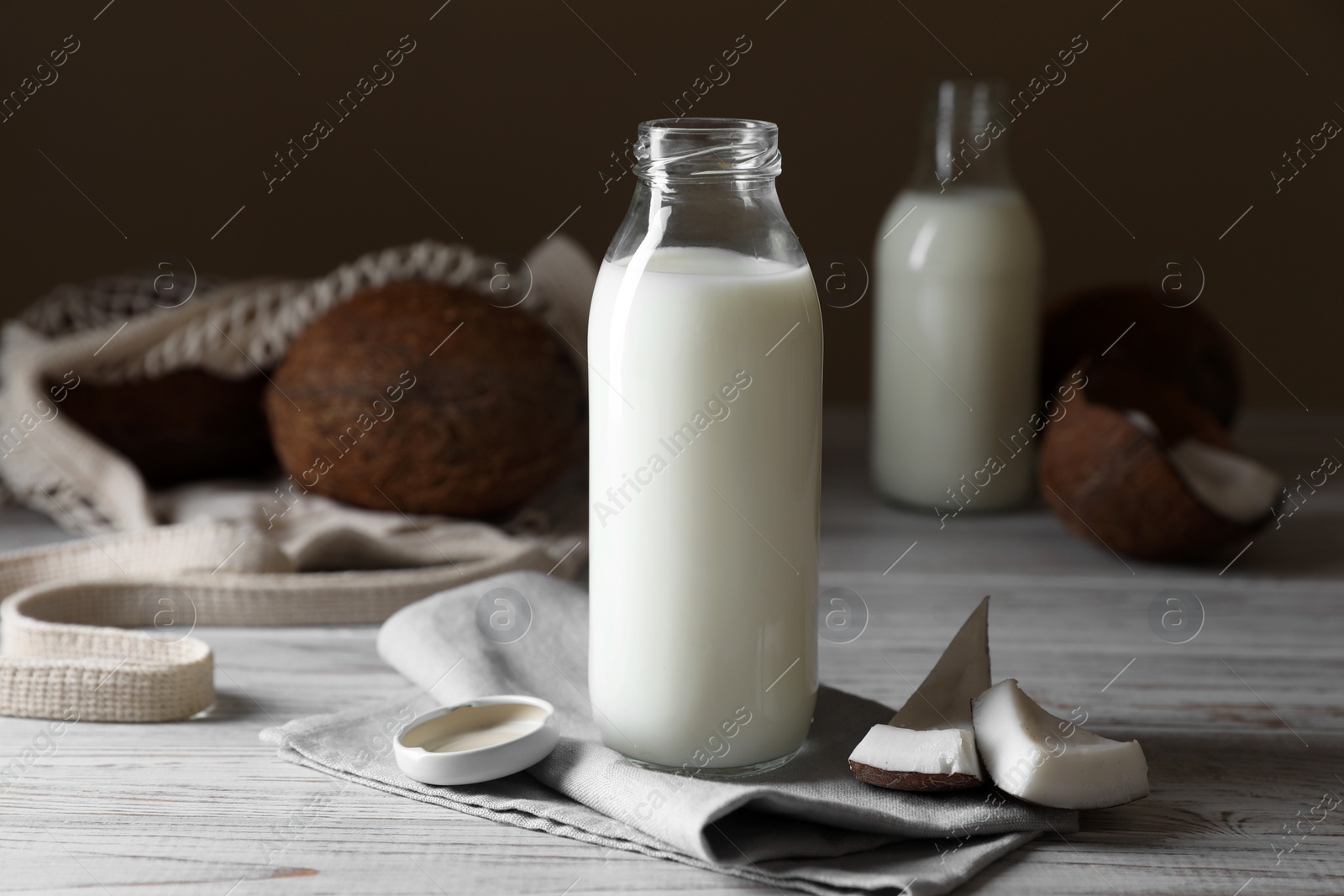 Photo of Coconut milk and nuts on white wooden table