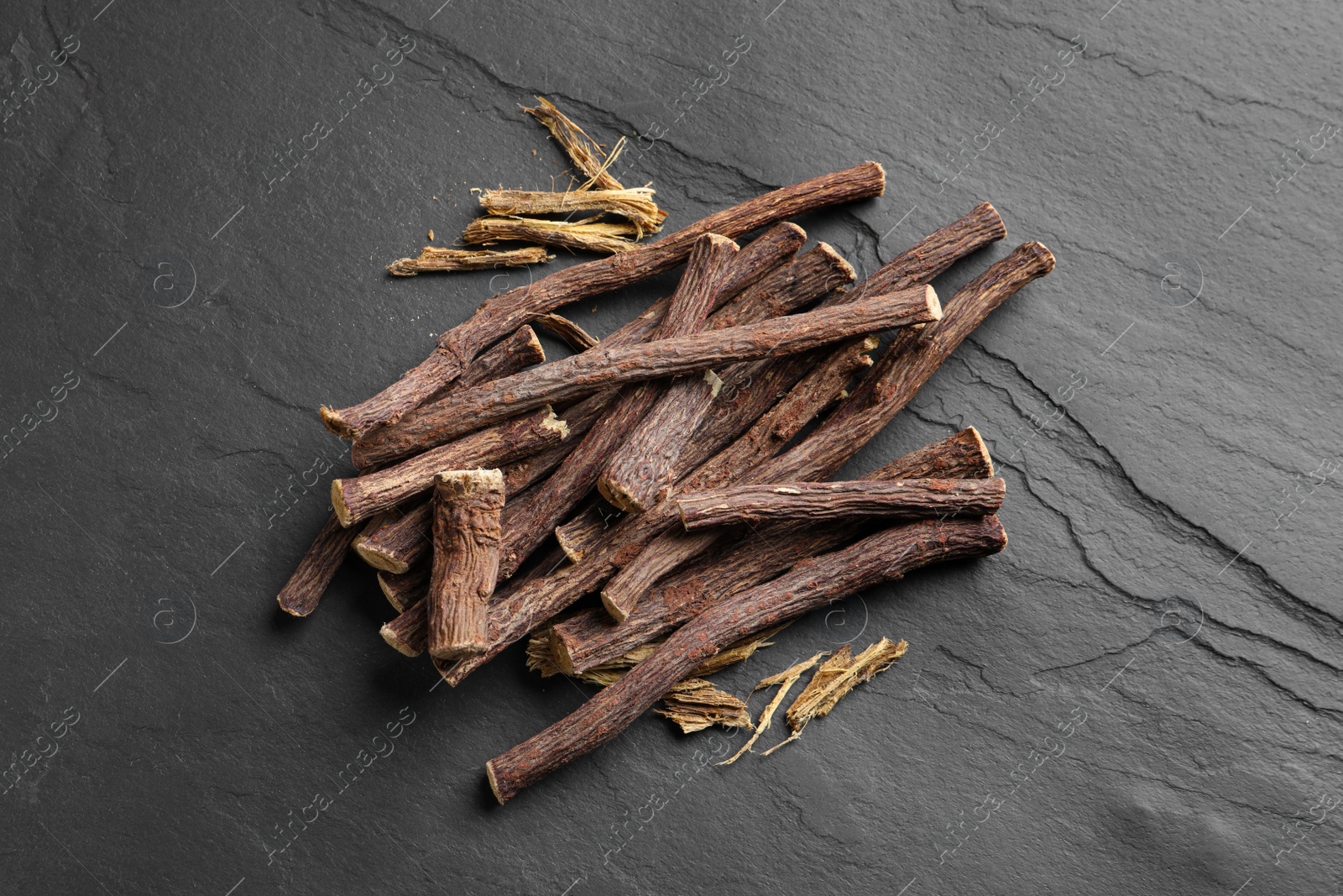 Photo of Dried sticks of liquorice root on black table, flat lay