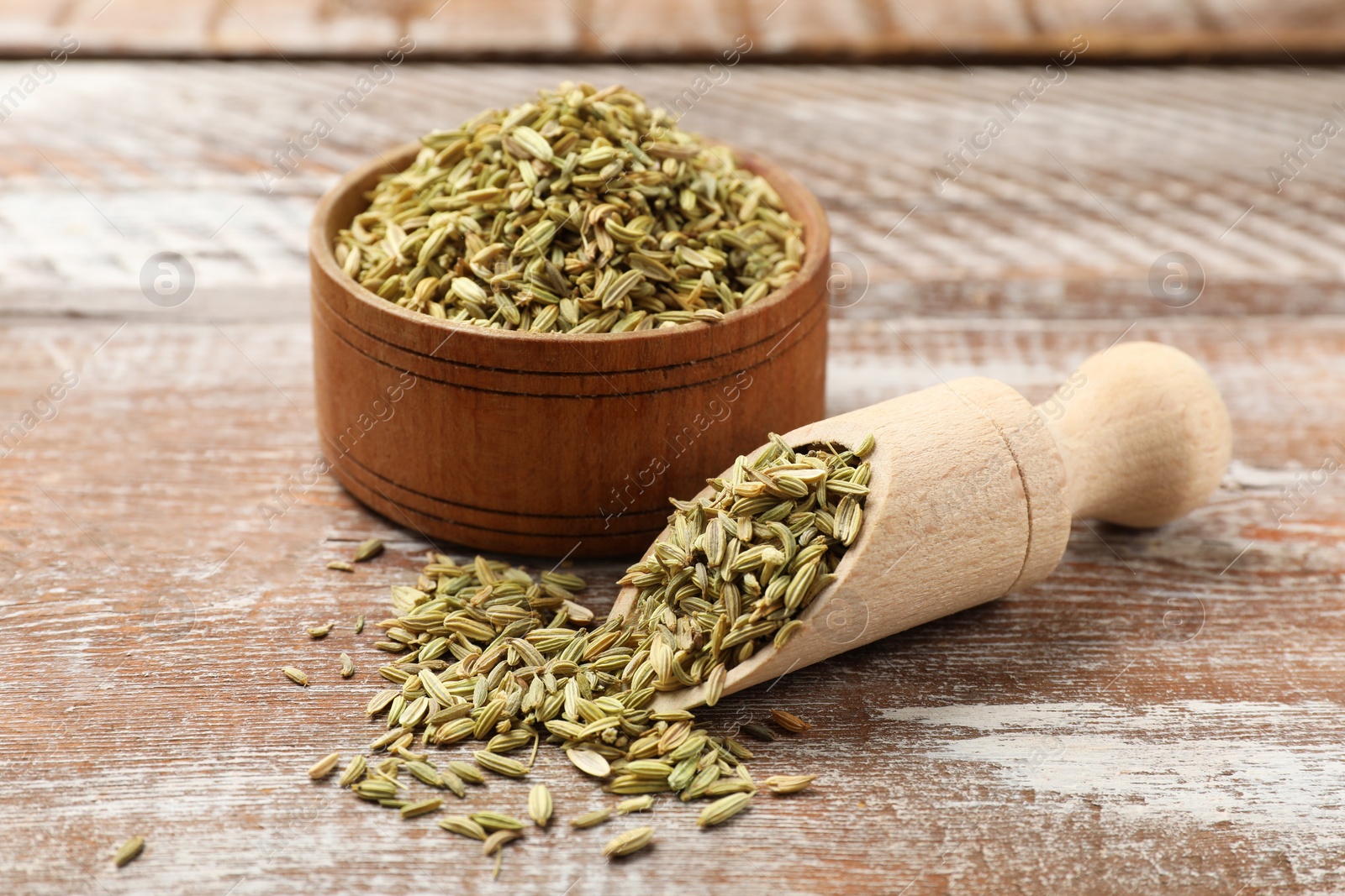 Photo of Bowl and scoop with fennel seeds on wooden table, closeup