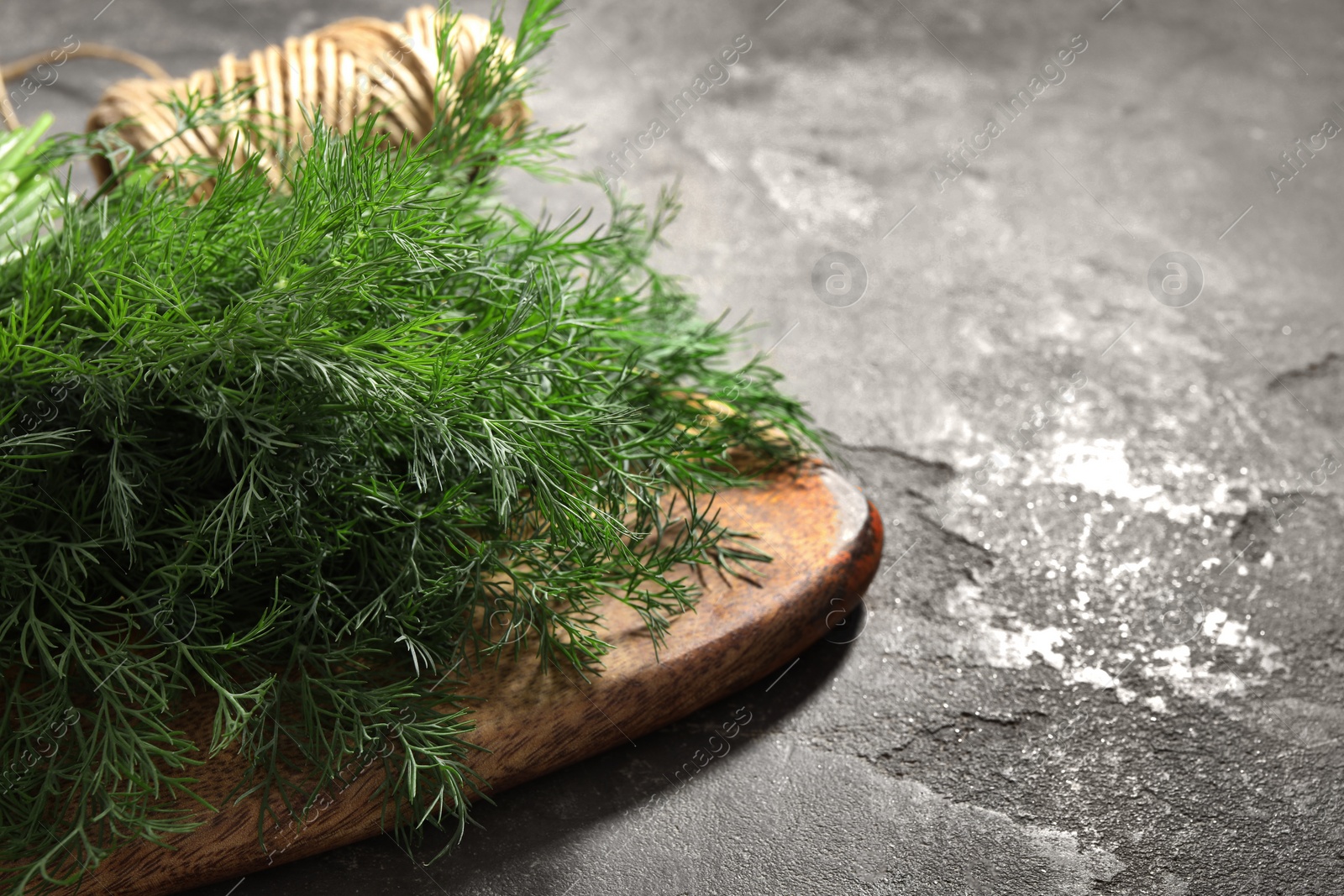 Photo of Fresh dill on grey textured table, closeup. Space for text