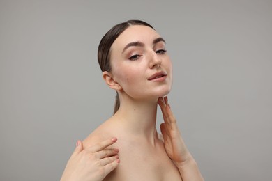 Photo of Beautiful woman touching her neck on grey background