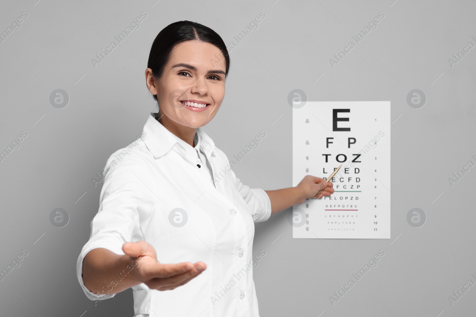 Photo of Ophthalmologist pointing at vision test chart on gray wall